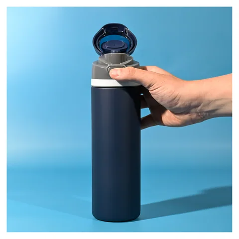 Navy insulated drink bottle held against a blue background